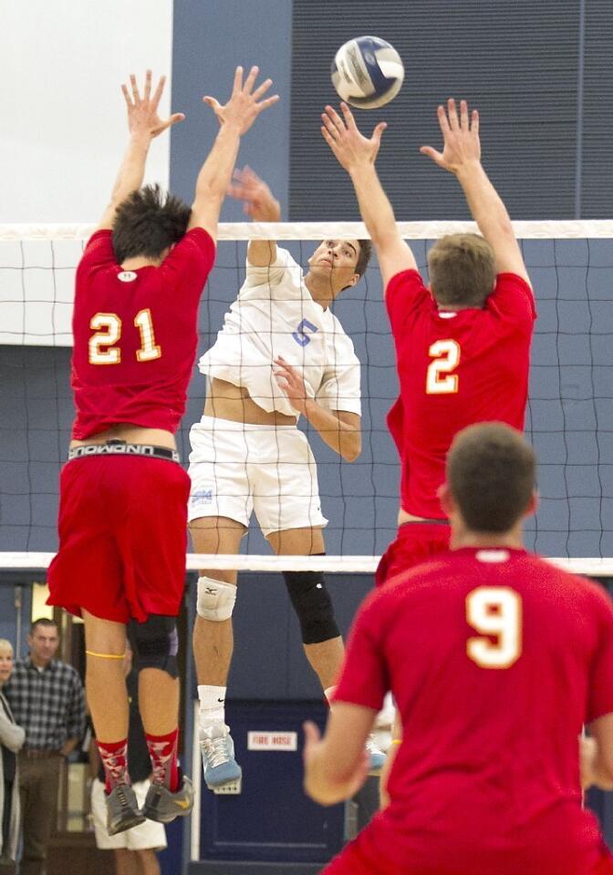 Corona del Mar High's Sam Kobrine (5) puts the ball between two Cathedral Catholic middle blockers.