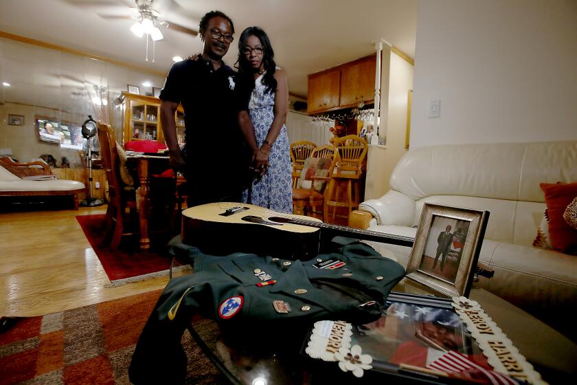 AZUSA, CALIF. - AUG. 8, 2021. Guiselle and Leroy Harris Jr, the parents of Leroy Harris III, with mementos of their son, including his dress uniform jacket, a guitar and pictures from his days in the military. A soldier in the U.S. Army, Leroy Harris III was killed in action in 2004 in Iraq. (Luis Sinco / Los Angeles Times)