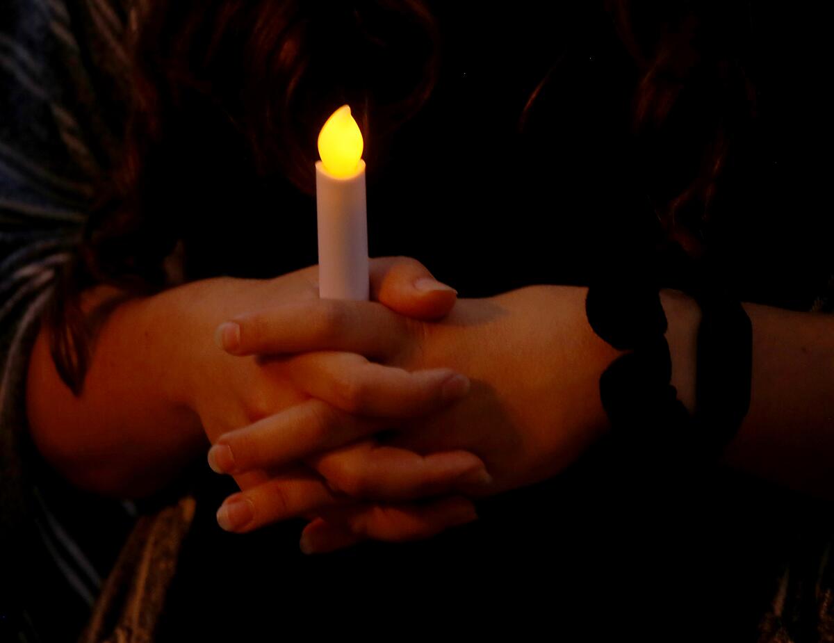 Hands are clasped around a fake candle