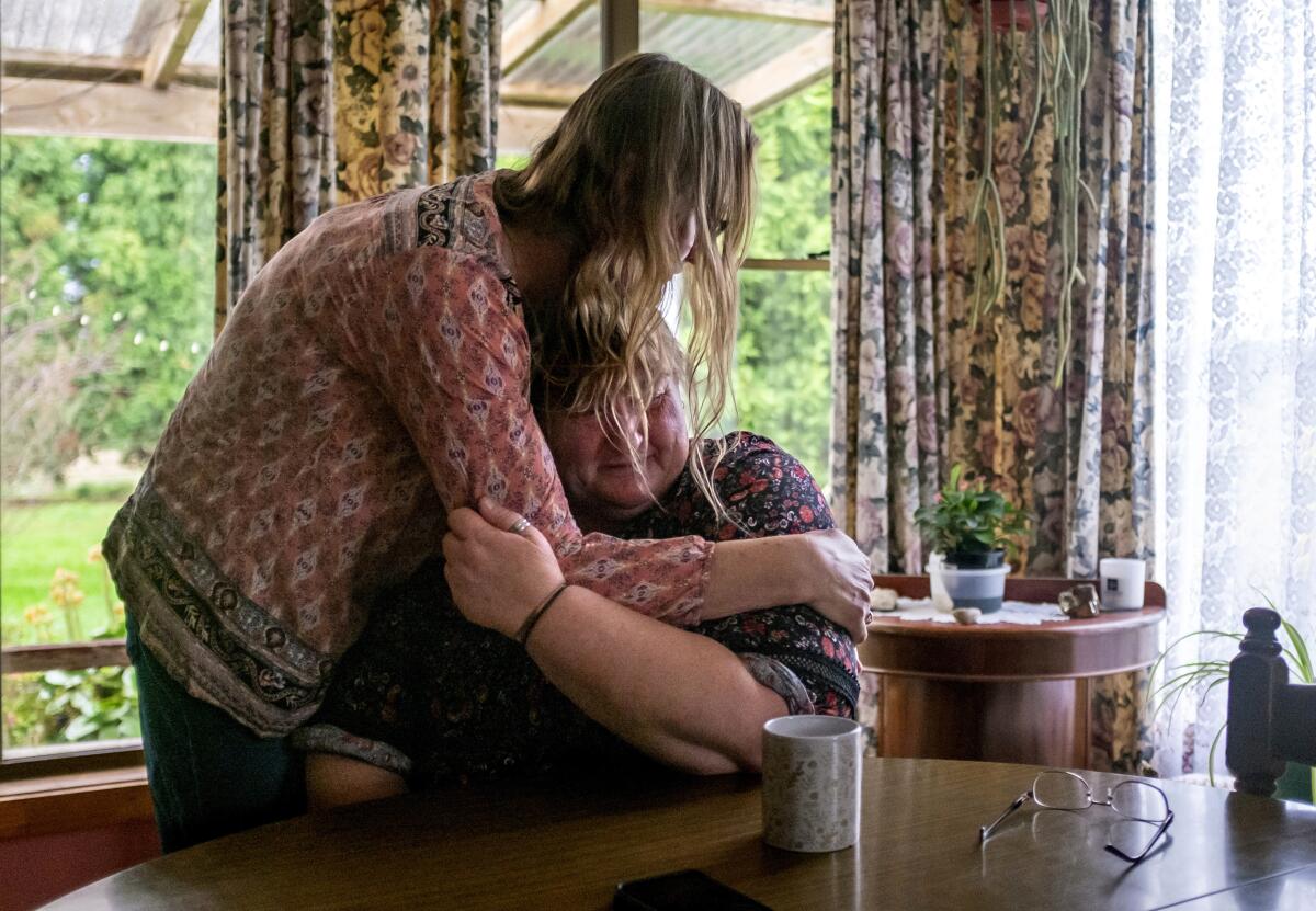 Carmall Casey, right, is embraced by Maxine Piper, a longtime friend and a source of support through Casey's addiction to opioids and battle with chronic pain, at her home in Black River, Tasmania, Australia, Tuesday, July 23, 2019. Casey doesn't know what she'll do when the pain returns. But she says she will never return to opioids. "I'm not going back," she says and begins to weep. "I'm not." (AP Photo/David Goldman)