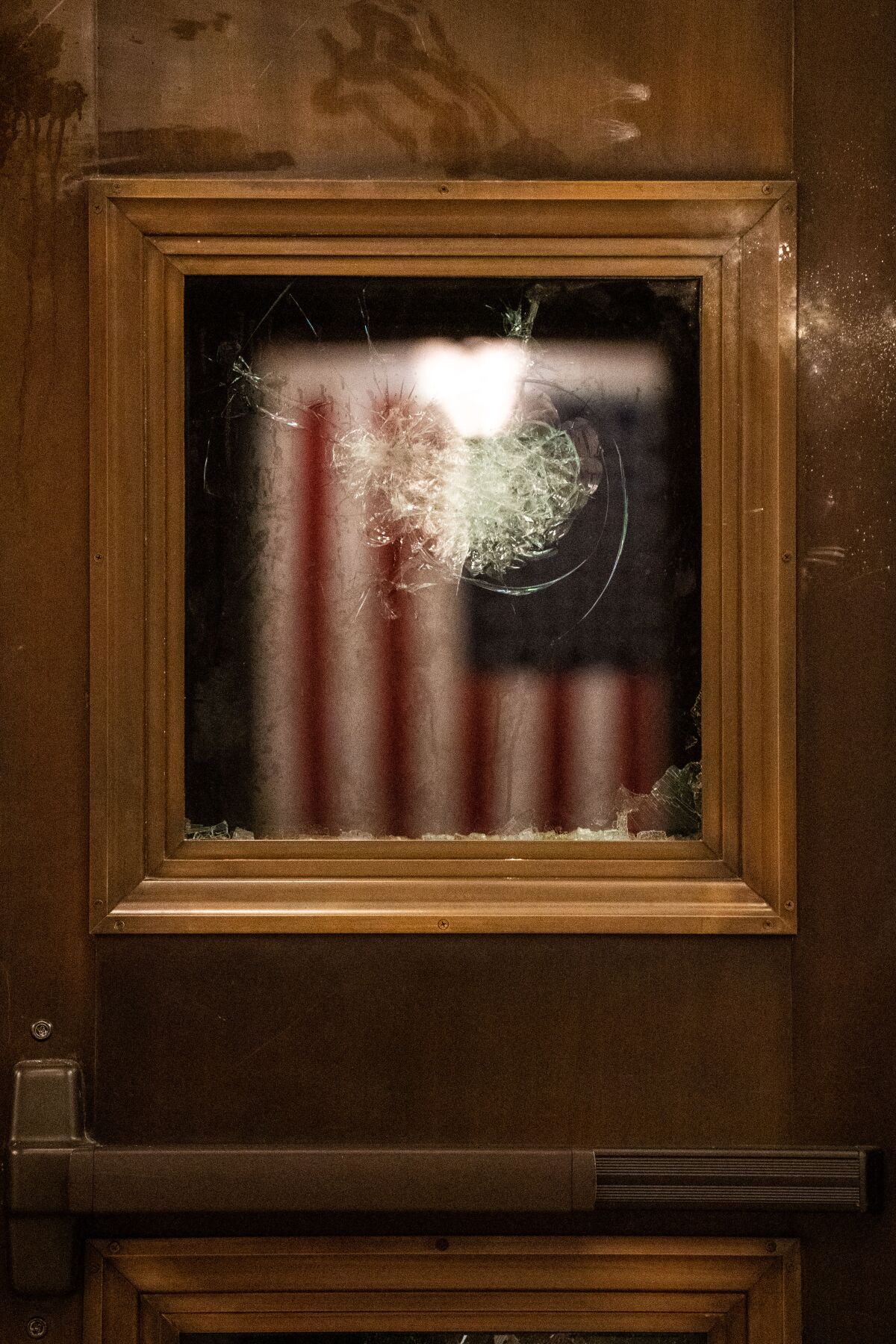 An American flag reflected in a broken window at the U.S. Capitol 
