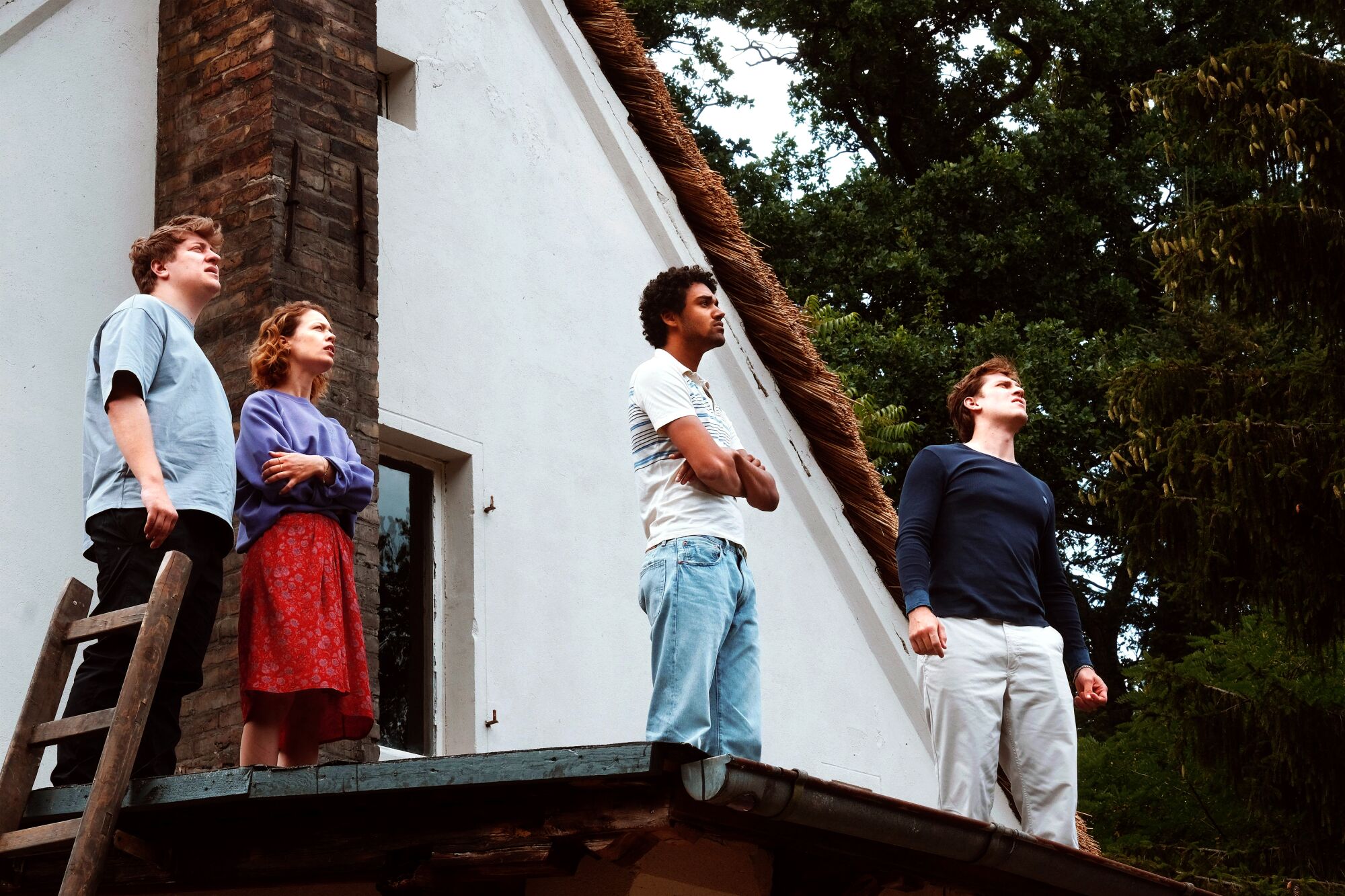 Four people on a balcony looking up at the sky.