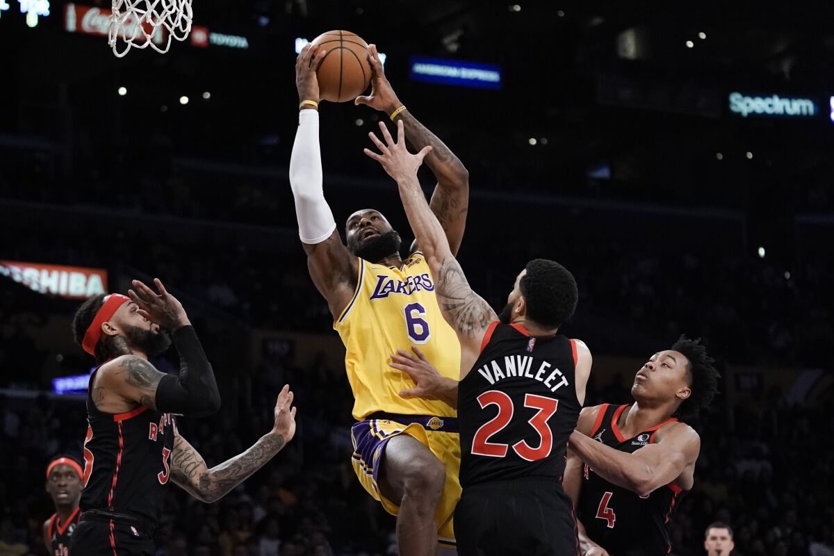 Los Angeles Lakers' LeBron James, center, left, goes up for a basket under pressure by Toronto Raptors' Fred VanVleet (23) during first half of an NBA basketball game Monday, March 14, 2022, in Los Angeles. (AP Photo/Jae C. Hong)