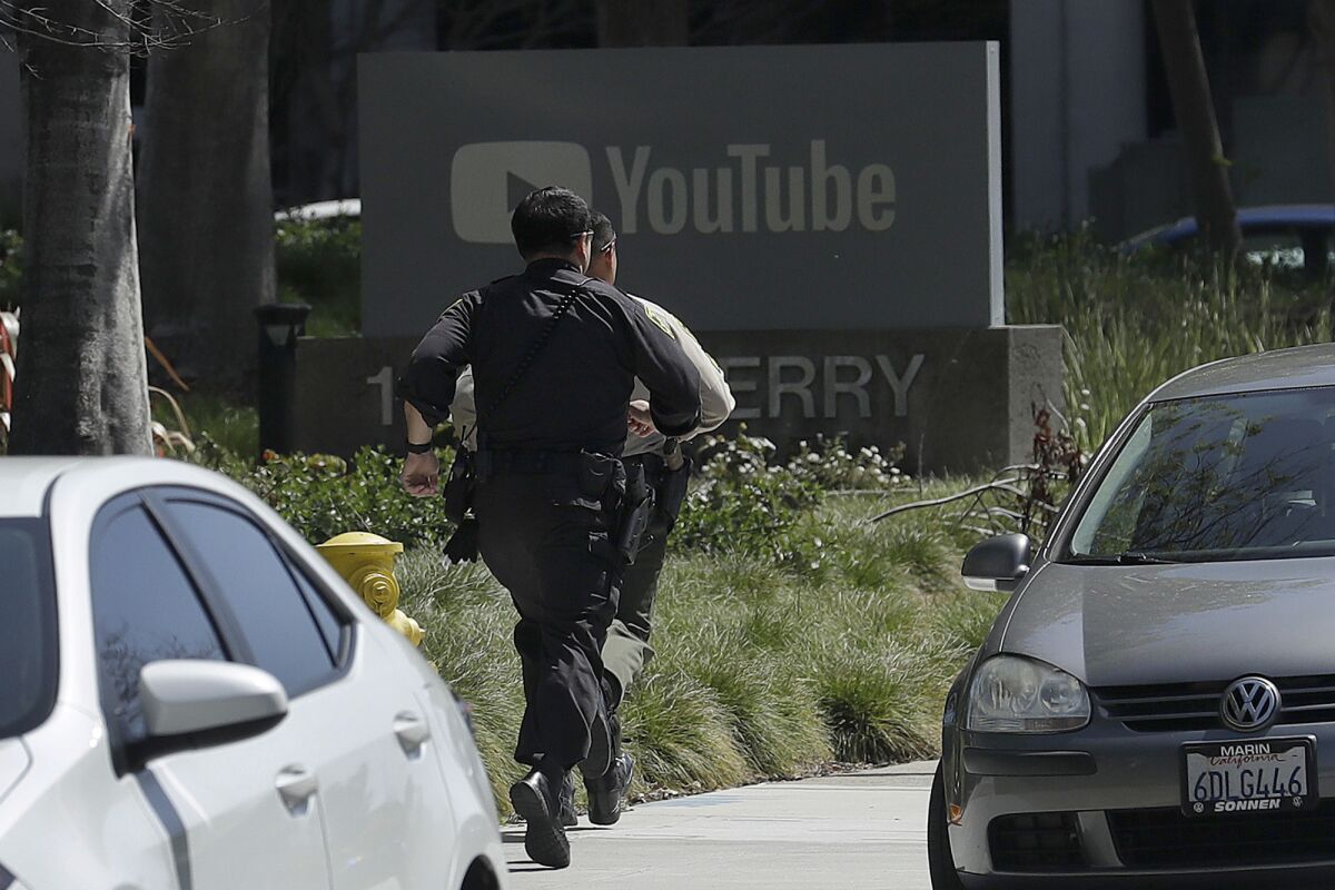 Police officers run toward a YouTube office in San Bruno on April 3.