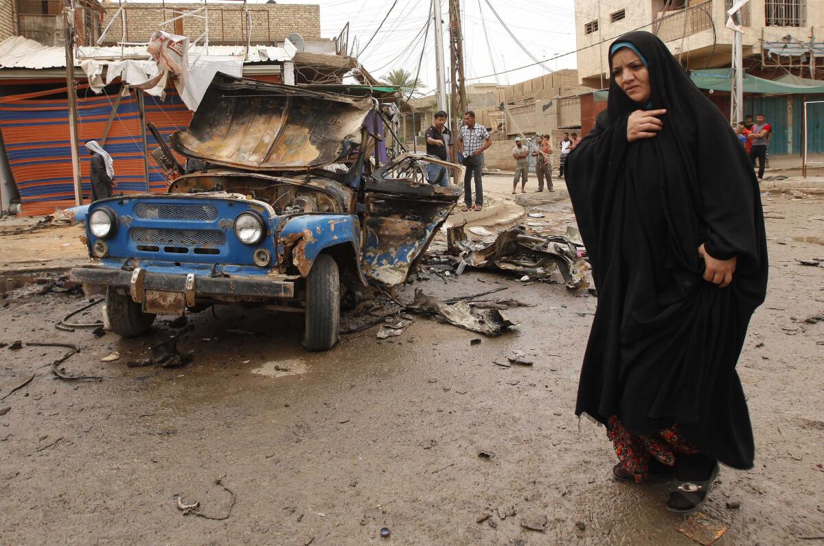 An Iraqi woman walks by the scene of a car bombing Monday in east Baghdad.