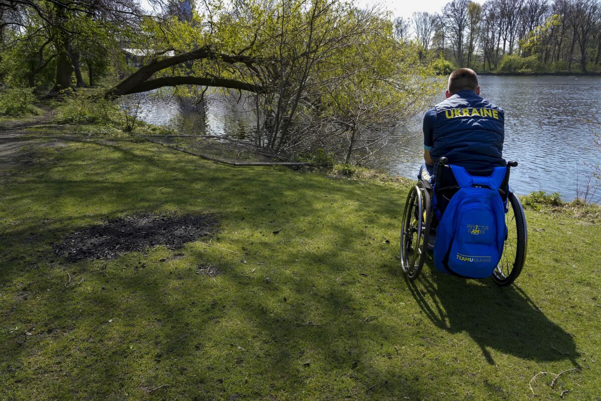 A member of Team Ukraine looks out over a lake at the Invictus Games venue in The Hague, Netherlands, Thursday, April 14, 2022. The week-long games for active servicemen and veterans who are ill, injured or wounded opens Saturday in this Dutch city that calls itself the global center of peace and justice. Those concepts seem a world away to the team of 19 athletes from Ukraine. (AP Photo/Peter Dejong)
