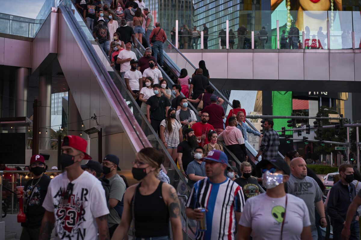 People ride an escalator along the Las Vegas Strip, Saturday, April 24, 2021, in Las Vegas. Las Vegas is bustling again after casino capacity limits were raised Saturday, May 1, to 80% and person-to-person distancing dropped to 3 feet (0.9 meters). (AP Photo/John Locher)