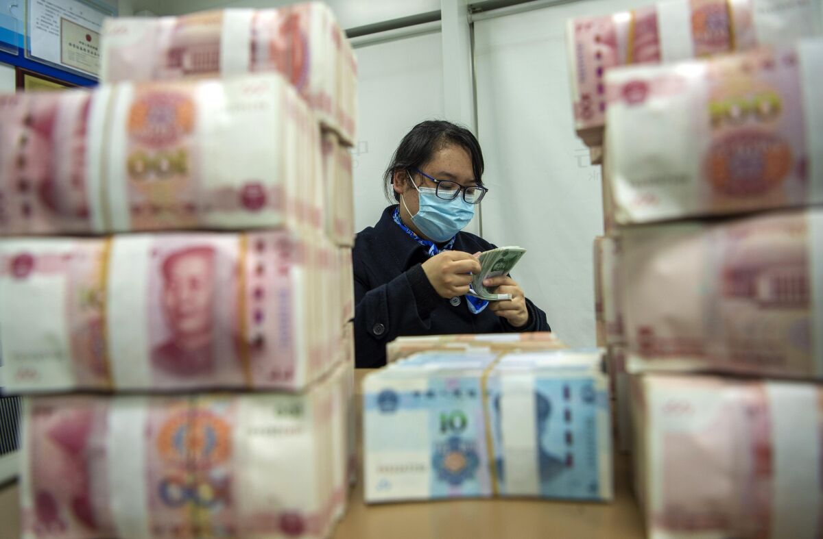 A clerk counts renminbi banknotes at a bank outlet in Hai'an city in eastern China's Jiangsu province, Monday, Dec. 6, 2021 China's central bank is trying to restrain the rise of the yuan after the currency hit a 2 1/2-year high against the dollar. (Chinatopix Via AP)