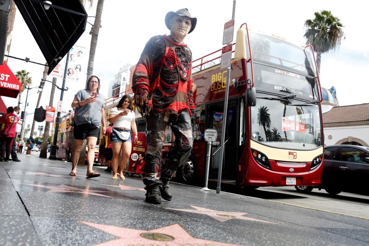 A performer walks along Hollywood Boulevard next to a Big Bus boarding area. London-based franchise Big Bus has opened operations in Los Angeles, challenging the city's biggest tour company, Starline.