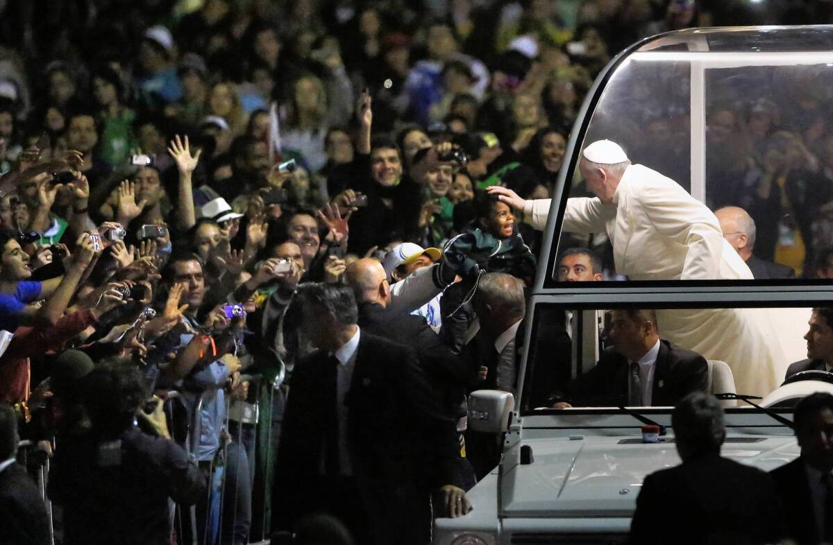 Pope Francis blesses a child from his popemobile as he arrives for a vigil on Rio de Janeiro's Copacabana beach.