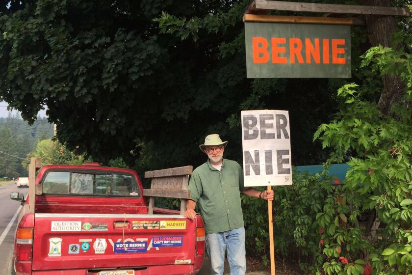 QUINCY CA AUGUST 9, 2017 -- Wayne Cartwright, 70, stands with his homemade Bernie Sanders sign and his pickup truck covered in progressive-themed bumper stickers outside his house in Quincy in conservative Plumas County. (Hailey Branson-Potts / Los Angeles Times)
