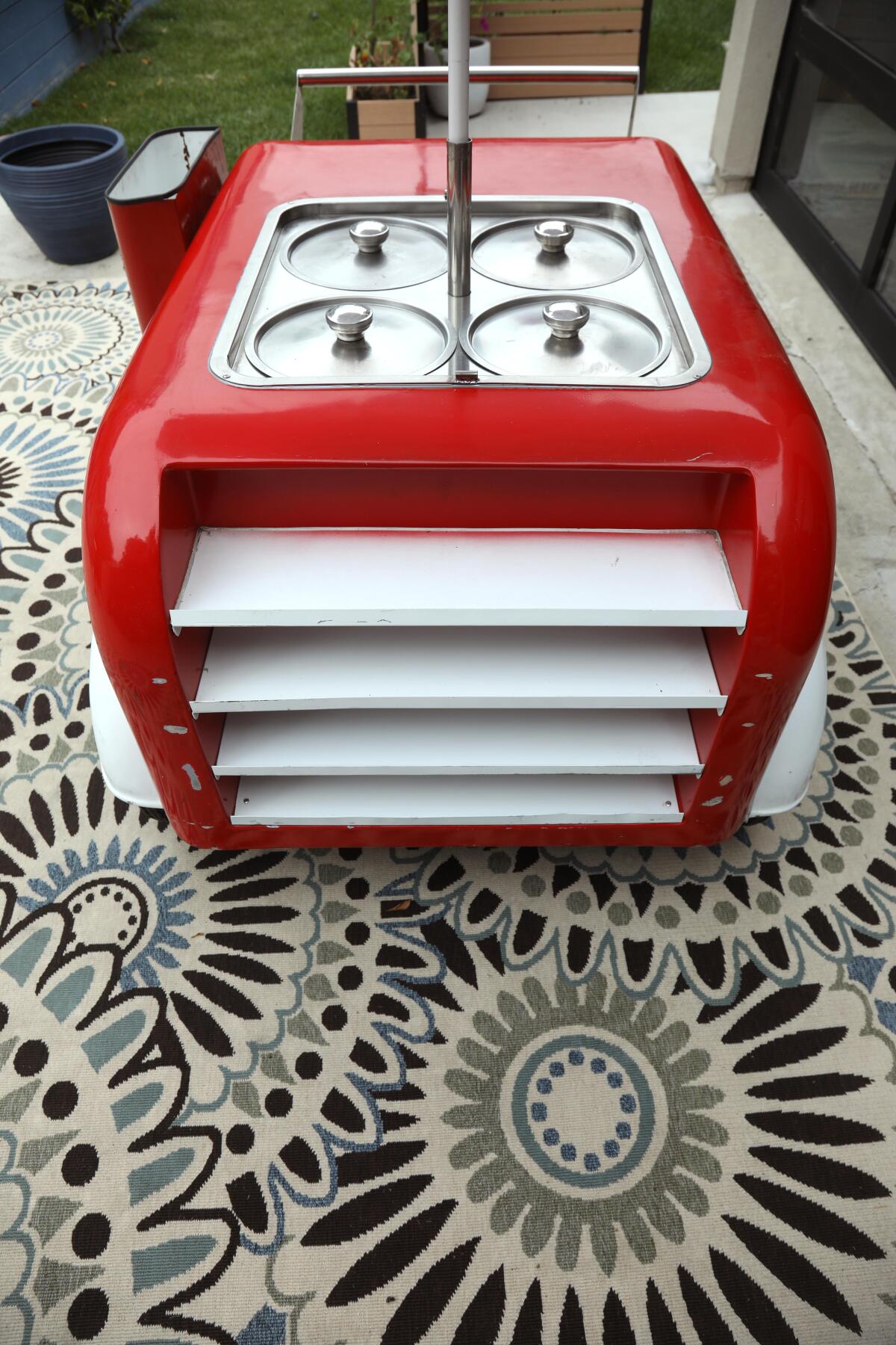 A red cart with four lids in the middle on its surface.