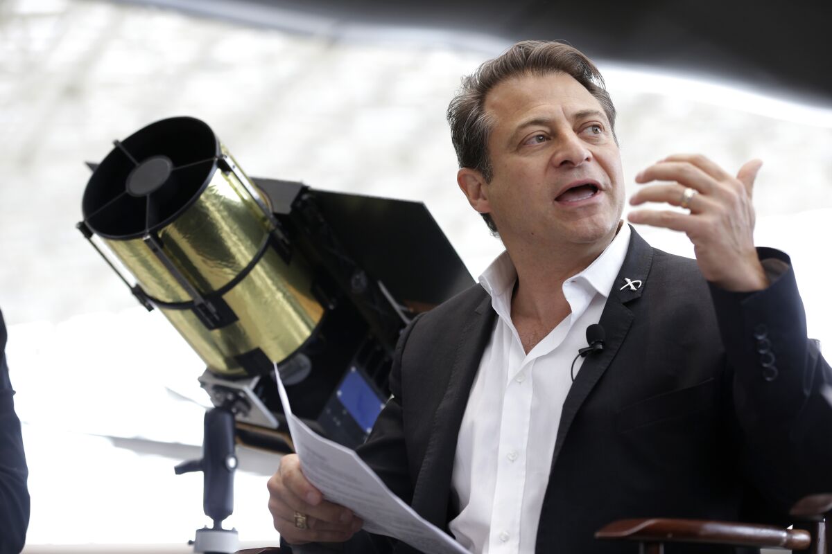 Peter Diamandis gestures and holds papers while speaking