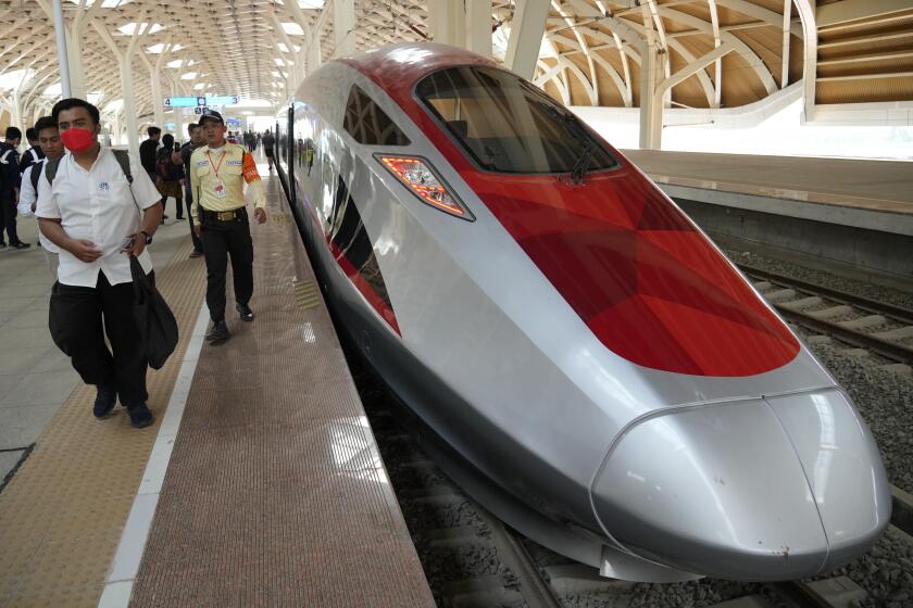 People walk near a high-speed train during a test ride at Halim station in Jakarta, Indonesia, on Sept. 18, 2023. Indonesia is launching Southeast Asia’s first high-speed railway, a key project under China’s Belt and Road infrastructure initiative that will cut travel time between the capital and another major city from the current three hours to about 40 minutes. (AP Photo/Achmad Ibrahim)
