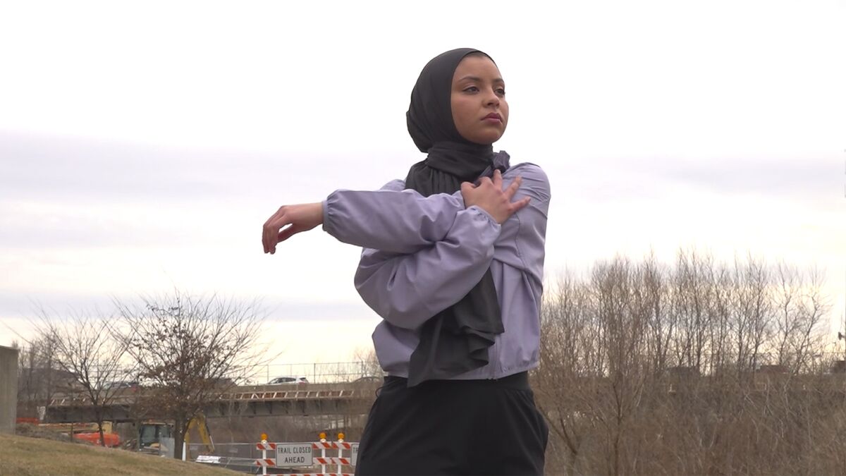 This image taken from video shows Noor Abukaram stretching her arm before running on a trail along the Olentangy River at Ohio State University on March 2, 2022. The woman disqualified from a cross-country race for wearing a hijab is celebrating a new Ohio law that stemmed from her experience. Noor Abukaram is a former high school athlete in suburban Toledo and is now an Ohio State student. Abukaram is Muslim and was disqualified from a 2019 high school race for wearing a hijab. It hadn't been an issue up until that point in the season. The law championed by state Sen. Theresa Gavarone forbids school sports regulators from requiring advance waivers or otherwise restricting participants' religious apparel unless it causes a “legitimate danger." (AP Photo/Patrick Orsagos)