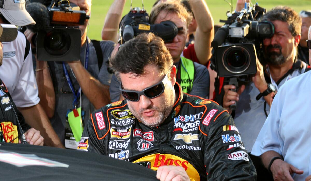 NASCAR driver Tony Stewart climbs into his car to prepare for the start of the Sprint Cup Series race surrounded by photographers and cameramen on Sunday night in Atlanta.