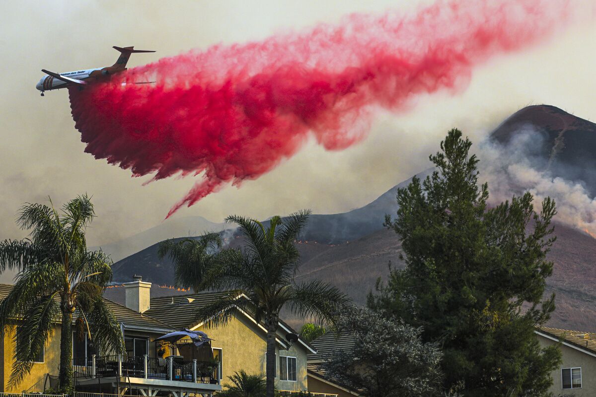 An air tanker fighting the Blue Ridge fire makes a fire retardant drop on Oct. 27, 2020 behind homes in Chino Hills.