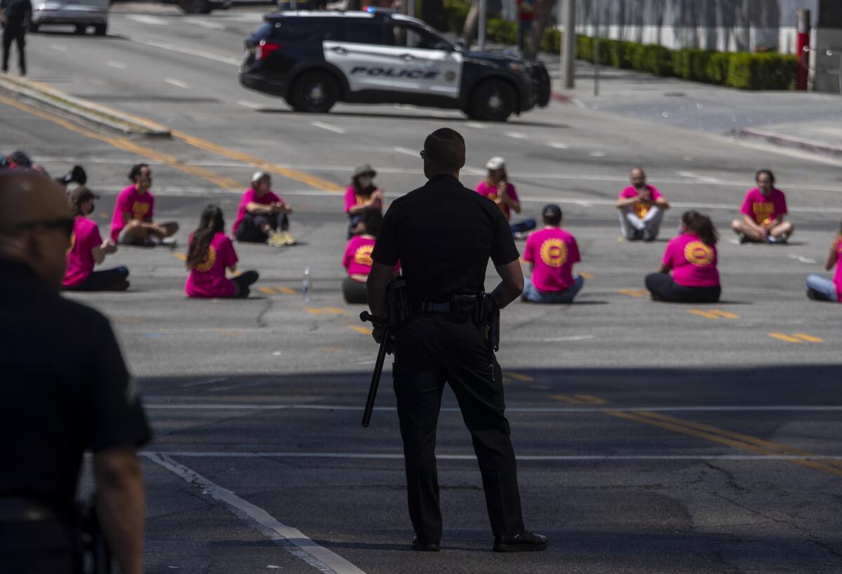 LAPD officers look at protesters sitting on the street