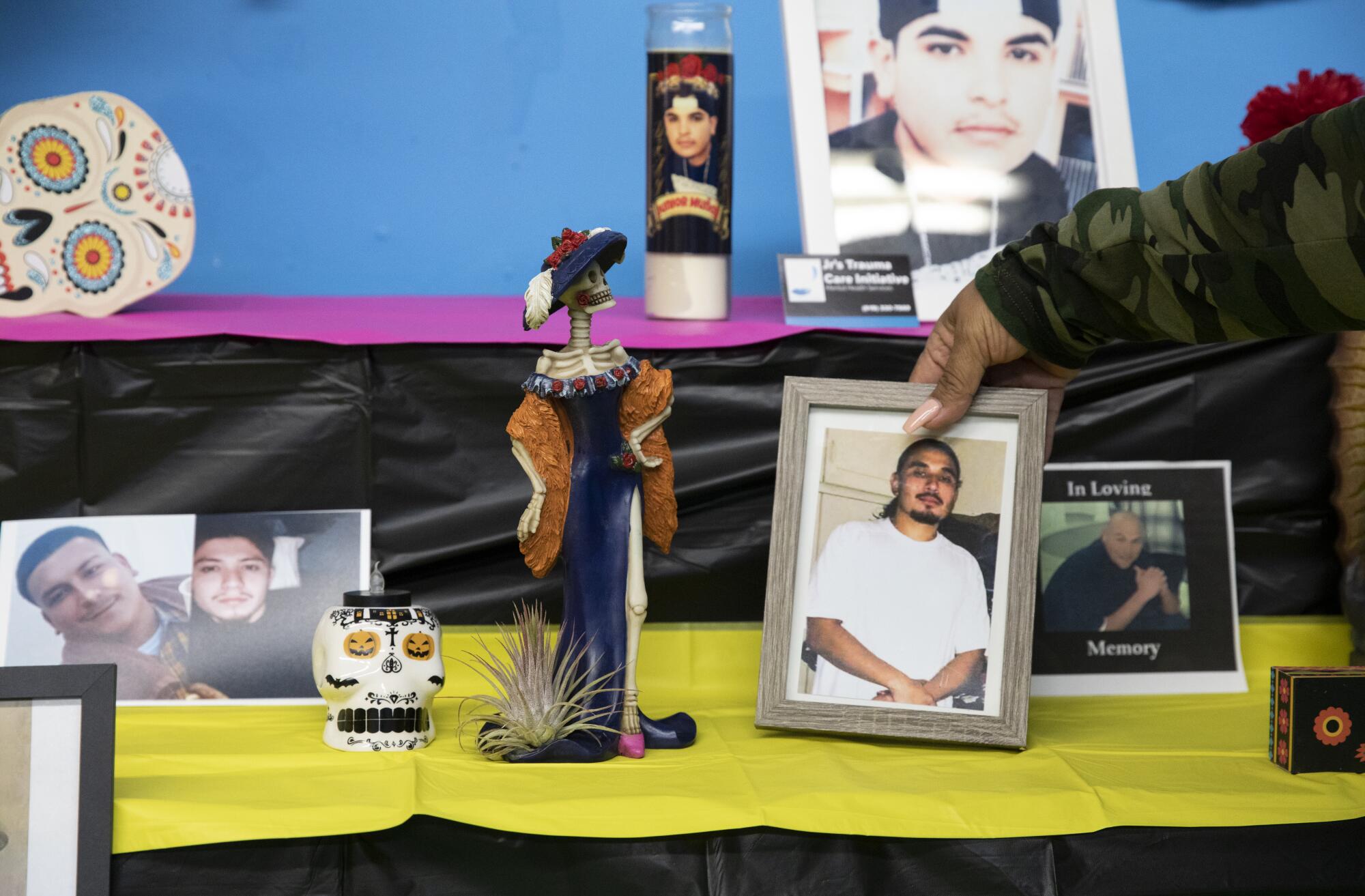 A hand straightens a photograph of a man on a Day of the Dead altar