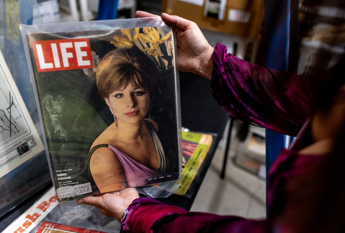Mara Papalas holds a Life magazine cover depicting Barbra Streisand.