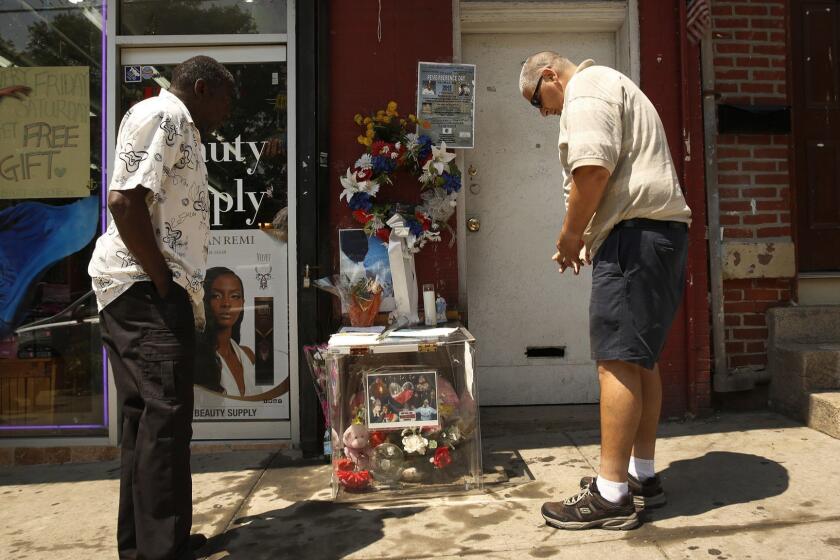 STATEN ISLAND, NEW YORK, NEW YORK--JULY 17, 2015--On Friday, July 17, 2015 James Corrar, right, stops to pray at the memorial site of his long-time friend Eric Garner on the anniversary of his death at the hands of New York police on Staten Island. Corrar had known Garner for over twenty years and said, "If you knew him like I did, he was a big teddybear." "He died for all the people in the world who believe they are being taken advantage of by the police." (Carolyn Cole/Los Angeles Times)