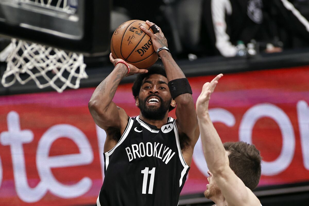 FILE - Brooklyn Nets guard Kyrie Irving (11) shoots against the Milwaukee Bucks during the second half of Game 1 of an NBA basketball second-round playoff series in New York, in this Saturday, June 5, 2021, file photo. Players like Kyrie Irving, who has refused to say if he will be vaccinated against COVID-19, will be subject to testing on all NBA practice, travel and game days this season. Fully vaccinated players will not. (AP Photo/Adam Hunger, File)