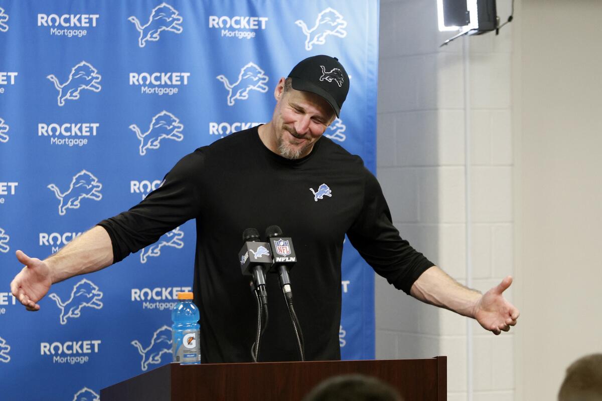 Detroit Lions head coach Dan Campbell addresses the media with arms stretched to his sides.
