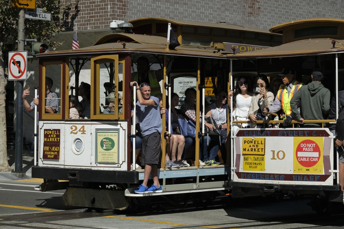 Two cable cars filled with tourists pass each other on San Francisco's Powell Street in September 2019.