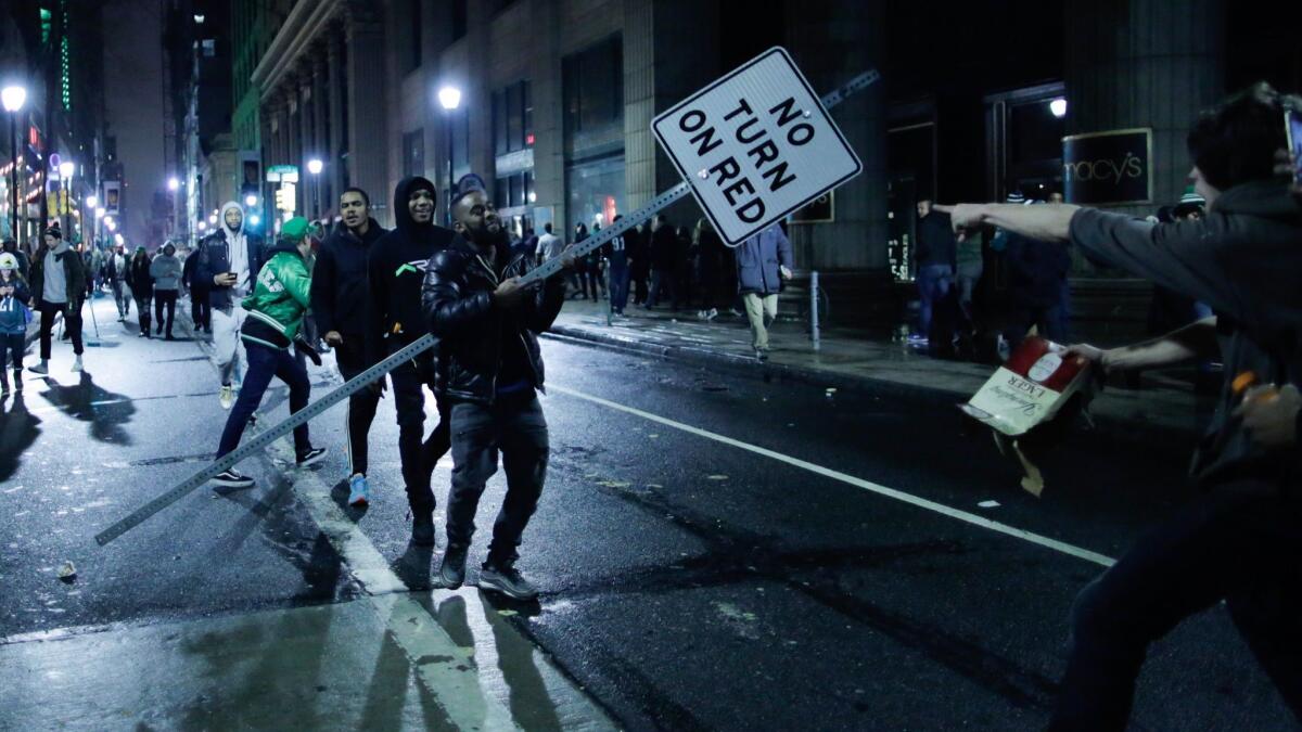 A man carries a traffic sign as Eagles fans celebrate victory in Super Bowl LII in Philadelphia.