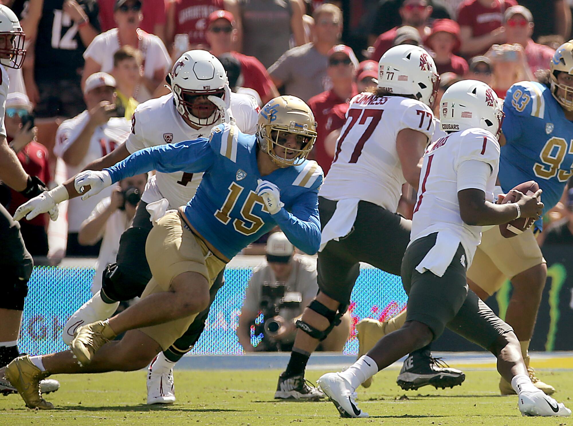 UCLA defensive end Laiatu Latu pushes past the offensive line and pursues Washington State quarterback Cameron Ward