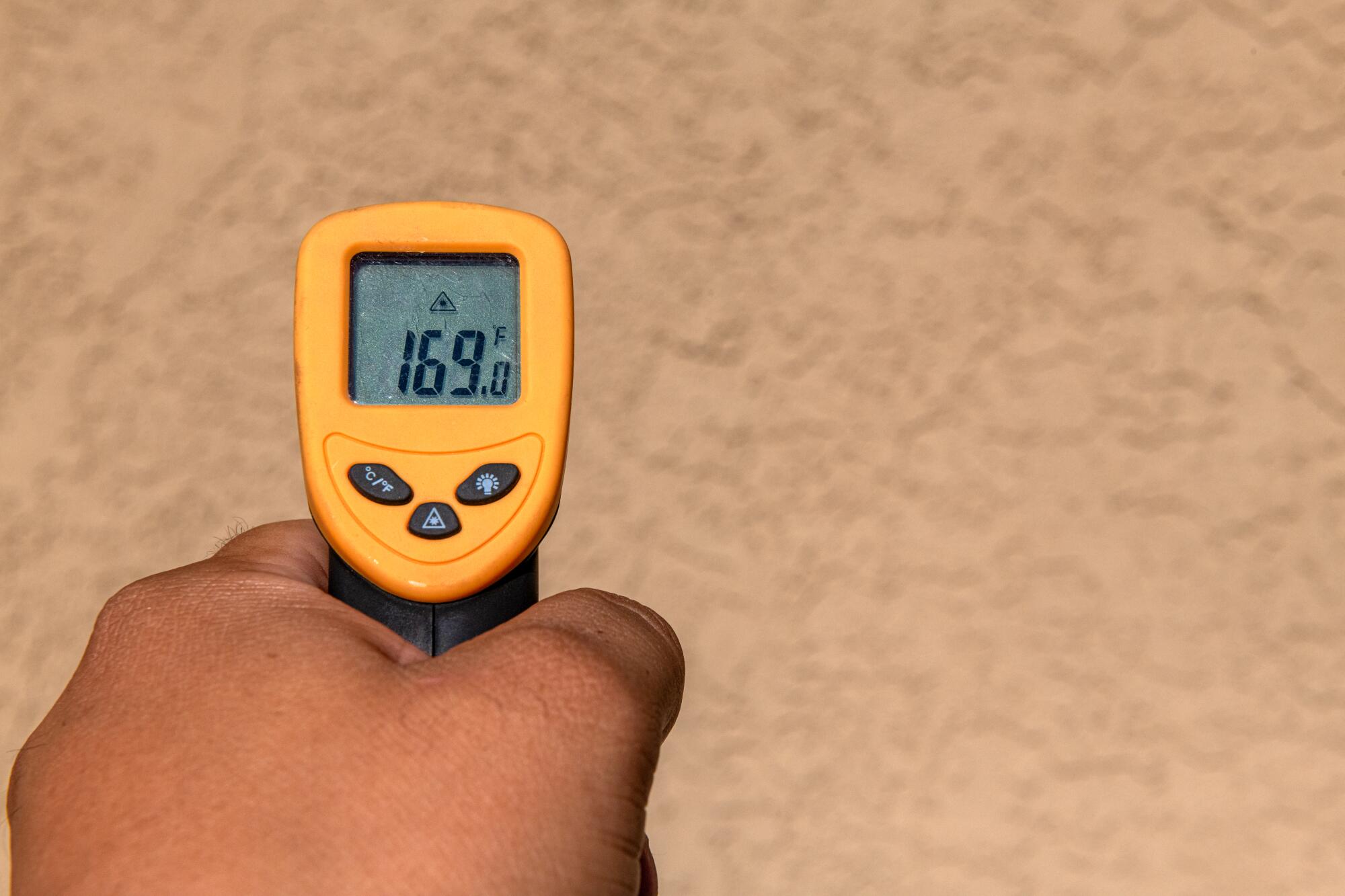 A hand holding a yellow thermometer that reads 169 degrees 