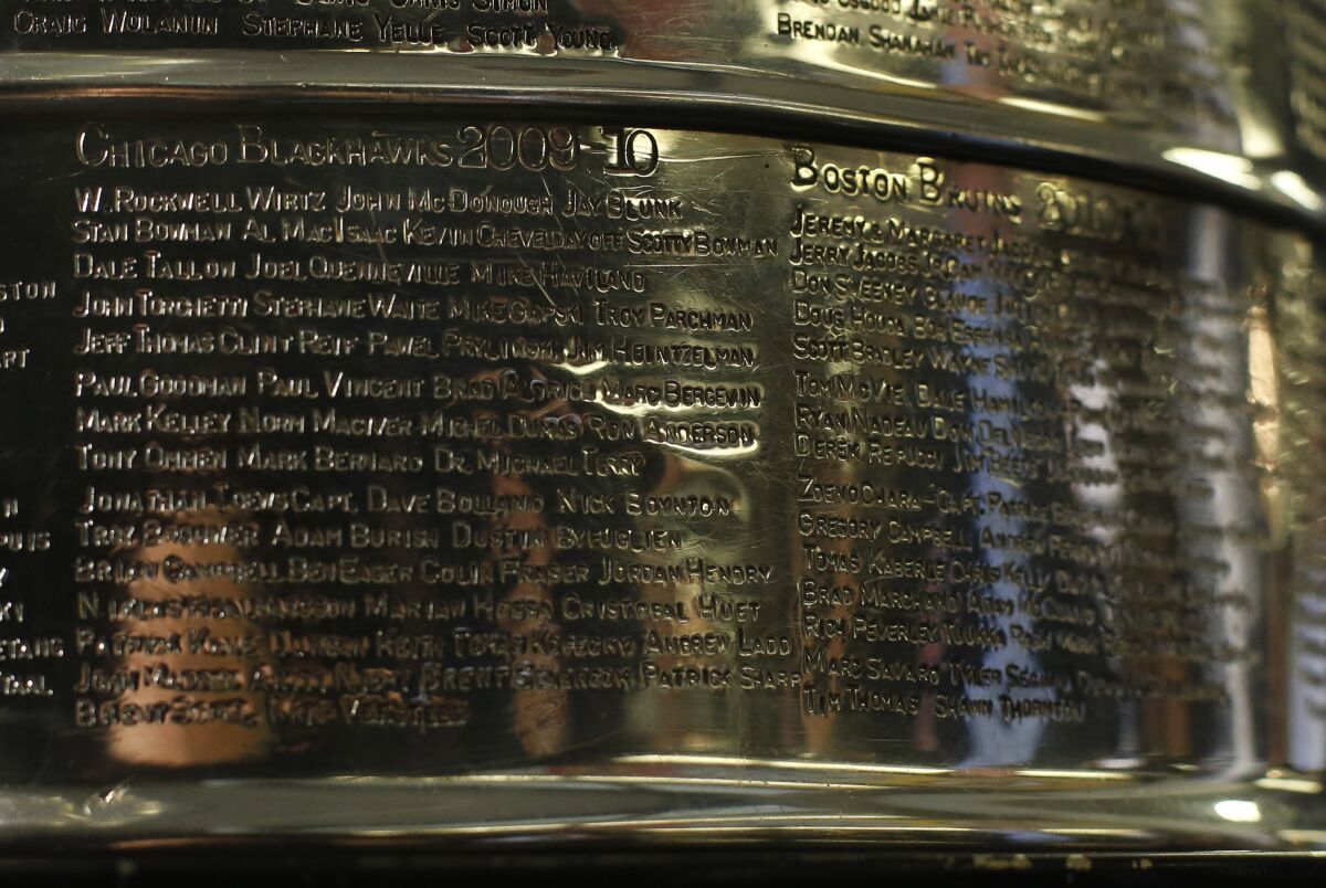 FILE - The names of the 2010 Stanley Cup Champion Chicago Blackhawks, left, are displayed on the Stanley Cup in the lobby of the United Center during an NHL hockey news conference on June 11, 2013 in Chicago. The first game of the Stanley Cup final series is Wednesday in Chicago. Blackhawks owner Rocky Wirtz wants the Hockey Hall of Fame to cover the name of an assistant coach engraved on the Stanley Cup after the assistant was accused of sexually assaulting a player during the team's run to the 2010 championship. (AP Photo/Charles Rex Arbogast, File)