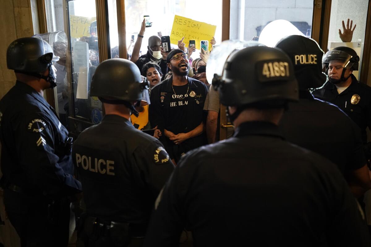 Protesters chant a slogan as they face off with police at the entrance of the Los Angeles City Hall in Los Angeles, Tuesday, Oct. 18, 2022. The demonstrators demanded the city council stop its virtual meeting Tuesday until two of its members resign over racist remarks. (AP Photo/Jae C. Hong)