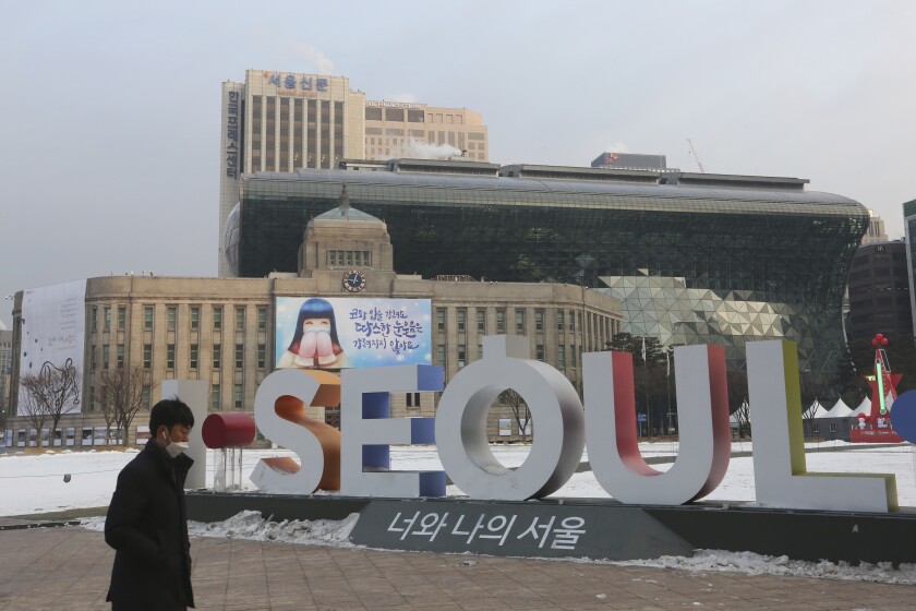 A man walks by the display of the capital city's logo near the Seoul City Hall in Seoul, South Korea, Tuesday, Jan. 12, 2021. The government of South Korea's capital is being criticized for a now-deleted online manual for pregnant women that contained sexist tips and gender stereotypes. (AP Photo/Ahn Young-joon)
