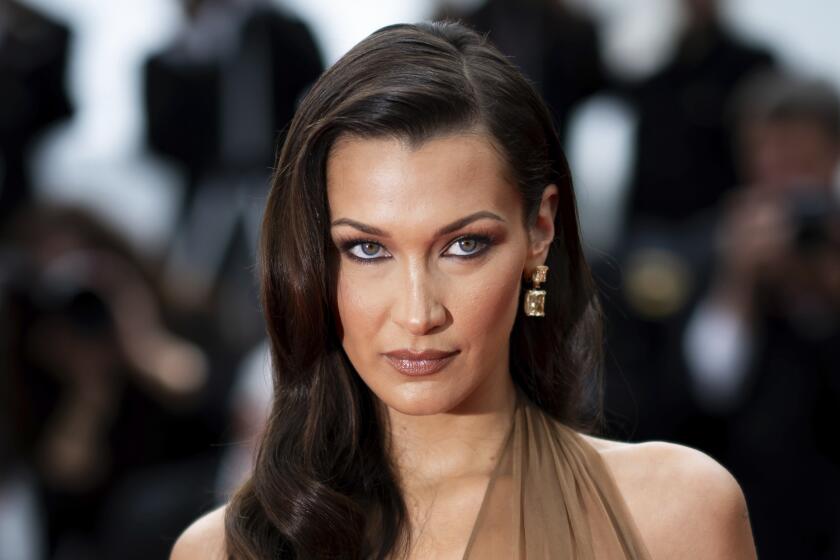 Bella Hadid gazing upward with brown hair parted to the side. 