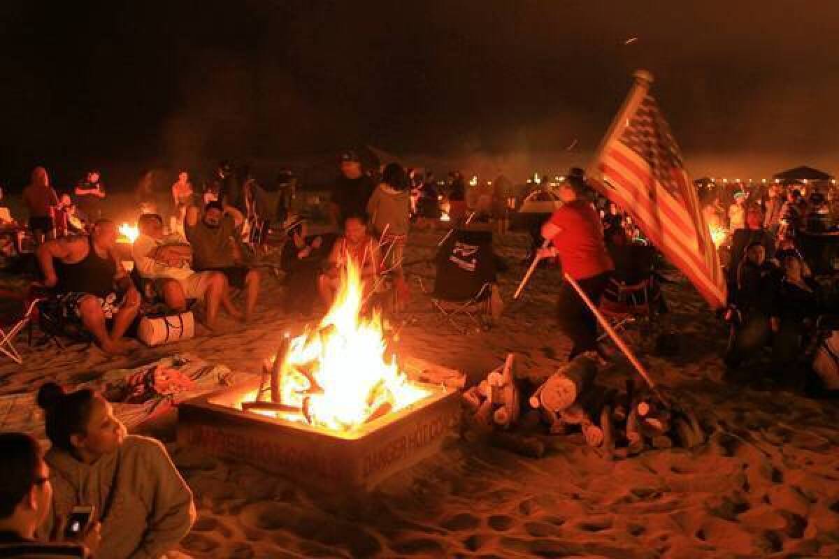 Beachgoers enjoy a bonfire in Huntington Beach over the Fourth of July weekend. Huntington Beach Mayor Connie Boardman says she and other Orange County mayors were told by air quality district staff that pollution from beach fire rings was not even in the agency’s top 100 concerns. “I wondered, then why are they spending so much time and effort pursuing this?” she said.
