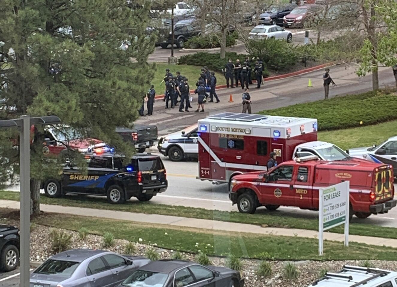 Armed police officers and others are seen outside STEM School Highlands Ranch, a charter middle school in the Denver suburb of Highlands Ranch, Colo., after a shooting Tuesday, May 7, 2019.