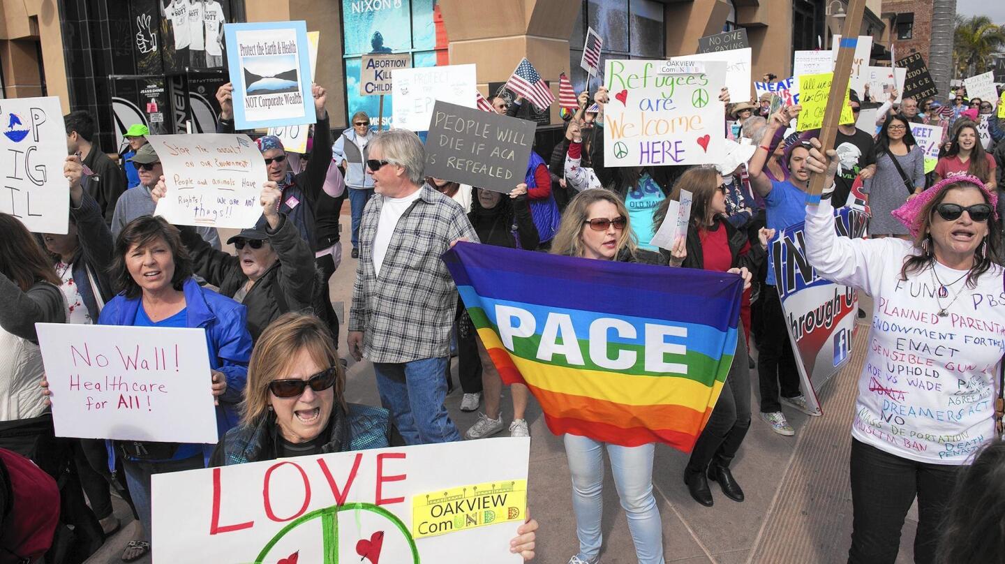 Protesters opposing President Trump and Rep. Dana Rohrabacher's (R-Costa Mesa) support of him march down Main Street in Huntington Beach on Monday.