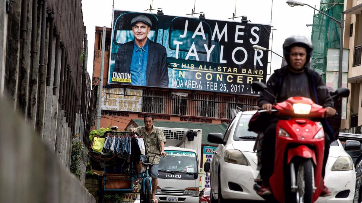A billboard in Manila promotes a concert by American singer James Taylor.