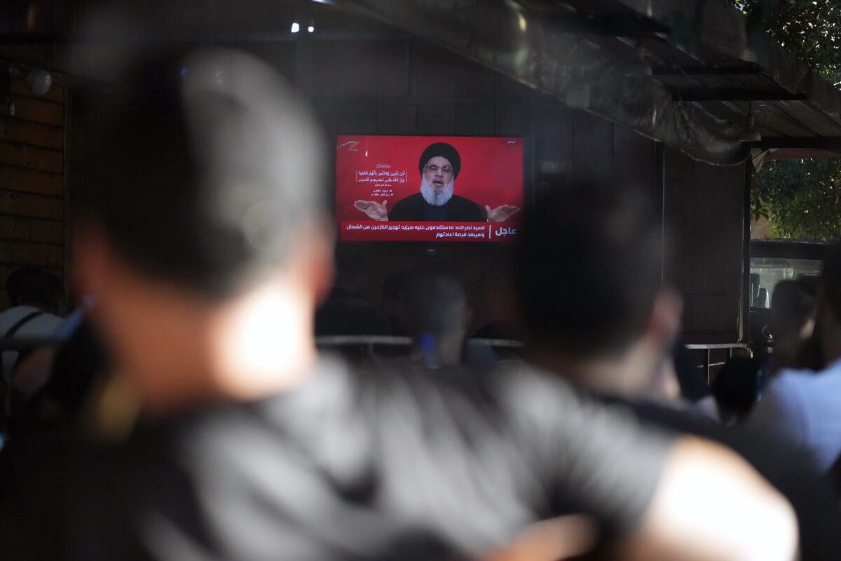 People watch the speech of Hezbollah leader Hassan Nasrallah on a tv screen as they sit in a cafe in the southern 