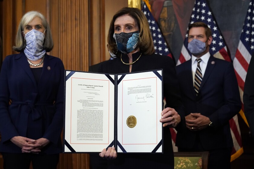 Nancy Pelosi, with two other lawmakers, holds open a folder with two pages and an official seal.
