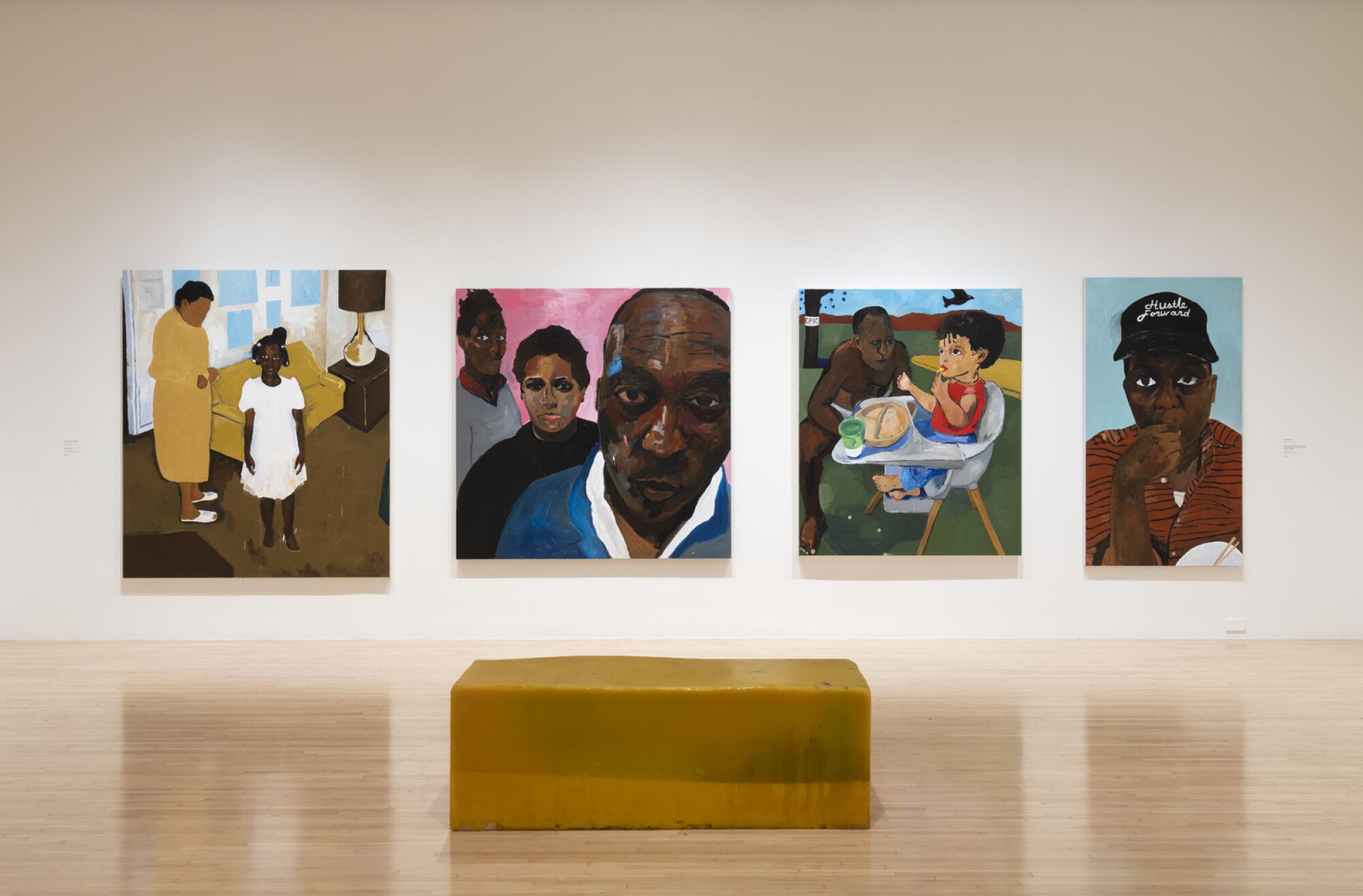 Eine Galerie zeigt vier Gemälde von Henry Taylor, die den Künstler und Familienmitglieder darstellen, sowie eine leuchtend gelbe Bank.