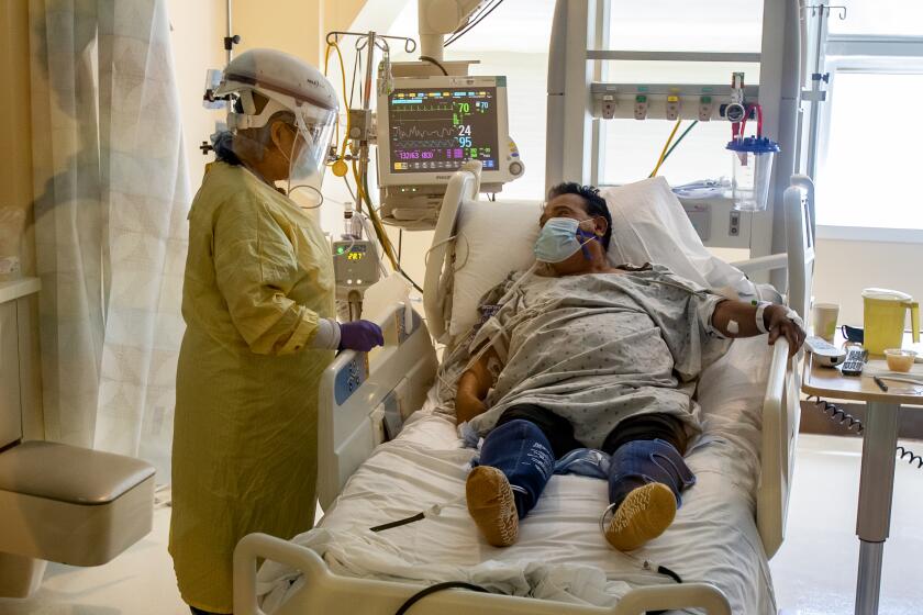 COLTON, CA - JULY 8, 2020: ICU nurse Lynda Tegan checks on COVID-19 patient Jose Mariscal, 66, who has been in the ICU for four days at Arrowhead Regional Medical Center on July 8, 2020 in Colton, California. This ICU has only 2 more beds available for Covid patients, but has the capacity to expand to more beds if needed.(Gina Ferazzi / Los Angeles Times)
