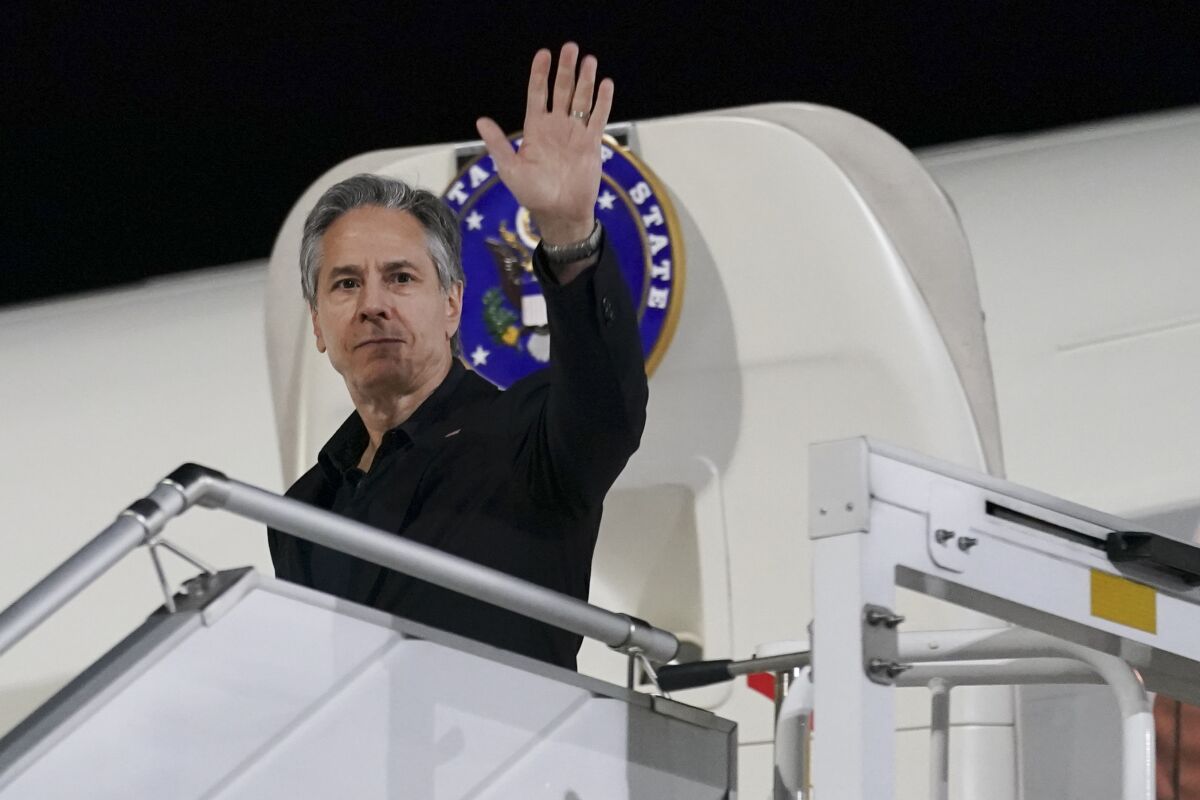 U.S. Secretary of State Antony Blinken waves as he exits a plane