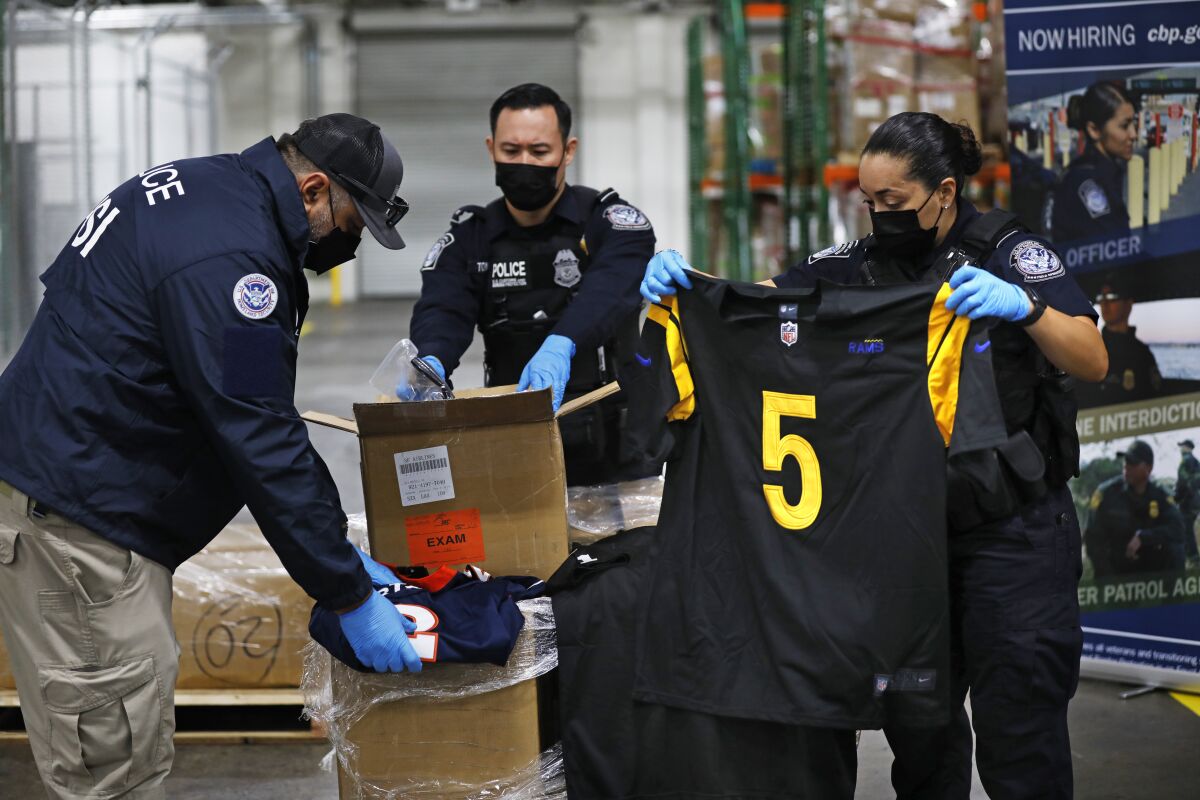 U.S. Customs and Border Protection officers open boxes of counterfeit goods.