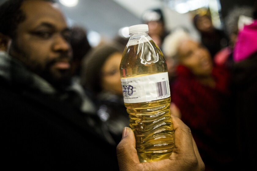   Un manifestante sostiene una botella de agua de grifo amarilla de Flint, Michigan, durante una manifestación. 