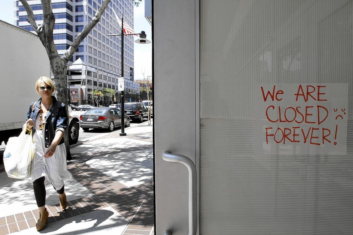 A woman carrying a Marshalls bag passes by the Old Navy store on 100 block of S. Brand Blvd. that has a sign that says "closed forever" on Thursday, May 29, 2014.