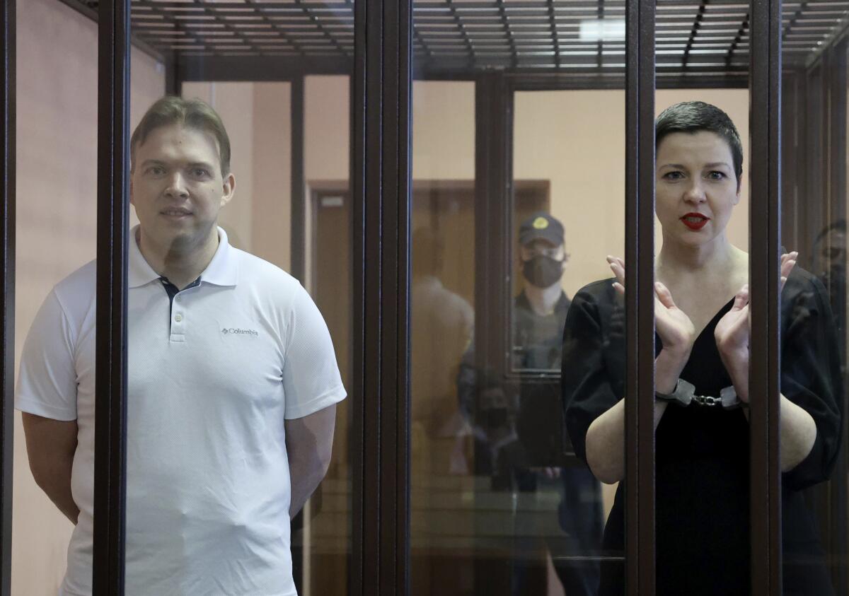 Maxim Znak and Maria Kolesnikova stand in a cage for defendants in court.