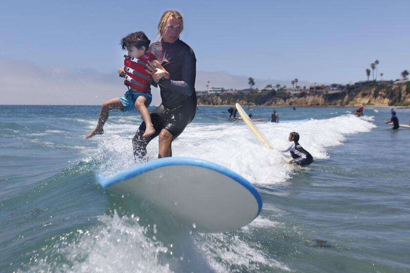 San Diego, CA - July 26: Volunteer instructor Ashton Pignat surfs with Joey Rohloff, 5, during the Surfers Healing camp at Tourmaline Beach on Wednesday, July 26, 2023. Surfers Healing, in its 27th year, hosts free surfing camps for children with autism on coastal cities the U.S. and internationally. The organization was founded by Izzy Paskowitz at the same beach in Pacific Beach where the children surfed on Wednesday. (K.C. Alfred / The San Diego Union-Tribune)