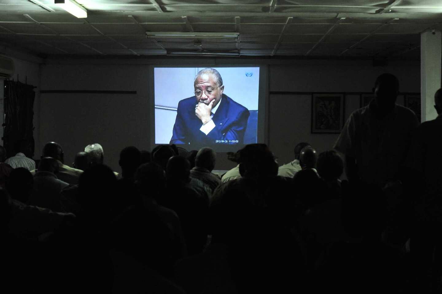People in Freetown, Sierra Leone, watch Charles Taylor, on screen, as his trial is broadcast from the Netherlands.